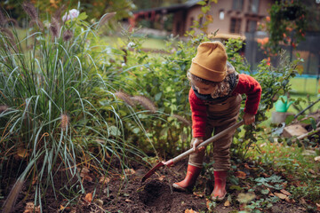 Petite fille prenant soin du potager, bêchant le sol.