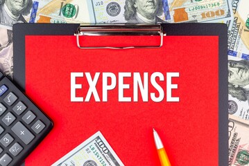 EXPENSE - word on the background of money (dollars), a notepad and a pen with a calculator. Business concept (copy space).