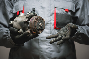 Auto mechanic showing a broken air conditioning compressor close up.