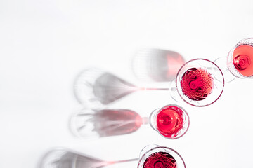 Glasses with pink red wine and sparkling shadows on white background. Shadows from glasses of wine on table. Flat lay, top view, copy space