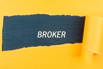 BROKER - text appearing behind torn yellow paper. Business concept: buying, selling, commerce (copy...