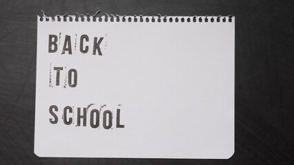blank page of a notebook with the phrase "Back To School" written in English on a black chalkboard background