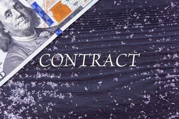 CONTRACT - word (text) on a dark wooden background, money, dollars and snow. Business concept (copy space).