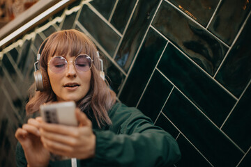 Young woman wearing headphones and enjoying listening to music indoors.