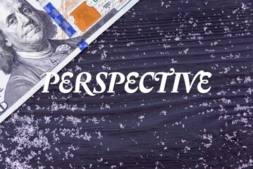 PERSPECTIVE - word (text) on a dark wooden background, money, dollars and snow. Business concept (copy space).