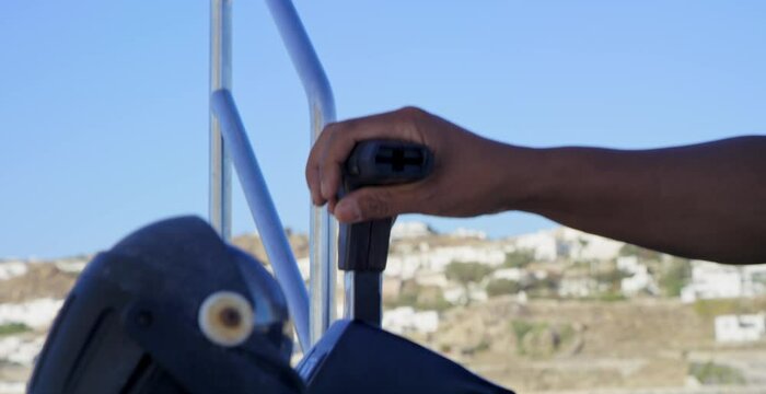 Male hand on boat throttle control with Santorini, Greece in background