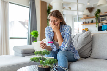 Shocked woman looking at control line on pregnancy test. Single sad woman complaining holding a pregnancy test . Depressed woman holding negative pregnancy test.