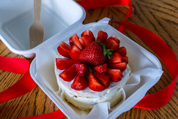 Small korean bento cake with strawberry. Delicious beautiful dessert. cake gift holiday. Korean style for one person. wooden fork cake for one person. Asian bento box cake, red ribbon.