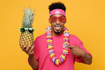 Young surprised fun man he wear pink t-shirt hawaiian lei sunglasses near hotel pool point index...