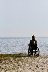 Person in wheelchair sitting and watching the sea