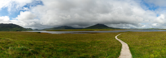 landscape of the Claggan Mountain Coastal Trail bog and boardwalk with the Nephir mountain range in...