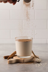 Cinnamon powder is poured into a glass with a cold drink based on Horchata rice.