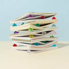 Books with colorful jewelry diamonds on pastel background. Minimal knowledge is wealth concept.