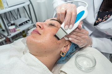 Obraz na płótnie Canvas beautician in gloves does a facial treatment with an ultrasonic spatula for a woman.