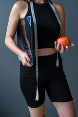  woman wearing black sports suit hold apple measuring tape weight isolated on background.