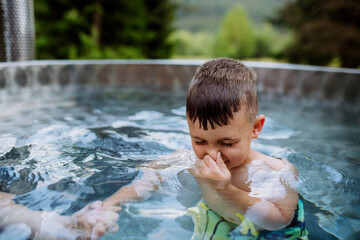 Little boy relaxing with eyes closed in hot tub, trying to dive. Summer holiday, vacation concept.