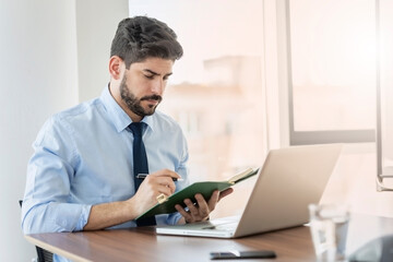 Businessman using laptop while sitting at desk and working at the office