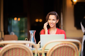 Brown haired attractive woman having a call while sitting at the outdoor cafe