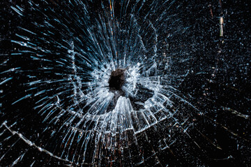 Bullet hole in a glass on the black background.closeup.