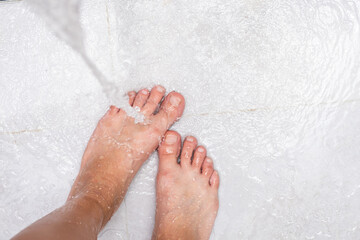 Woman washing feet, close up. Female stands under shower water.