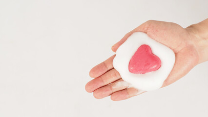 Hands with foaming soap and pink soap on white background. Studio shot