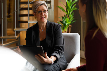 Businesswoman with tablet explaining to coworker in office