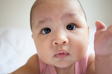 Asian cute baby in white sunny bedroom. Newborn child relaxing on bed