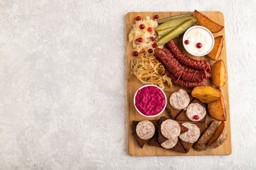 Fototapeta na wymiar set of snacks: sausages, toast, sauerkraut, marinated onion and cucumber, baked potato. Top view, copy space.