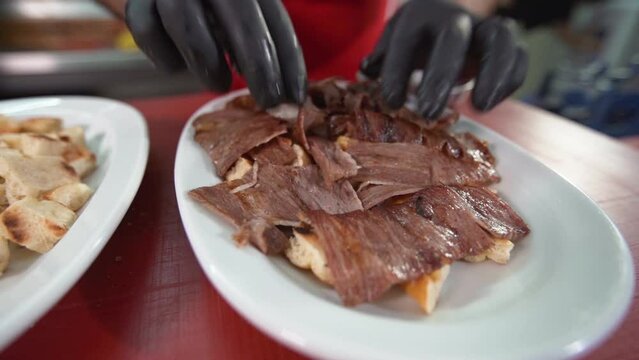 Turkey Iskender kebab. Chef.
Chef Iskender prepares the kebab. He places the meat on the pita.
