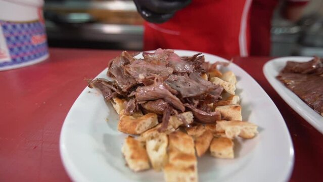 Turkey Iskender kebab. Chef.
Chef Iskender prepares the kebab. He places the meat on the pita.

