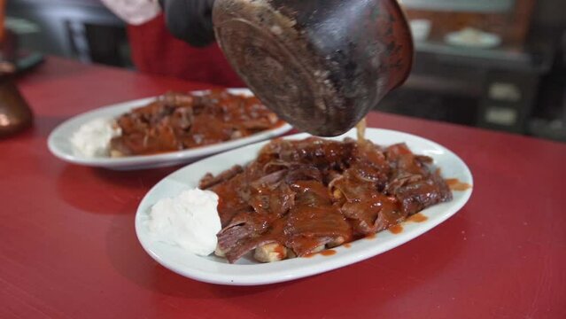 Turkey Iskender kebab. 
Pouring sauce on meat.
