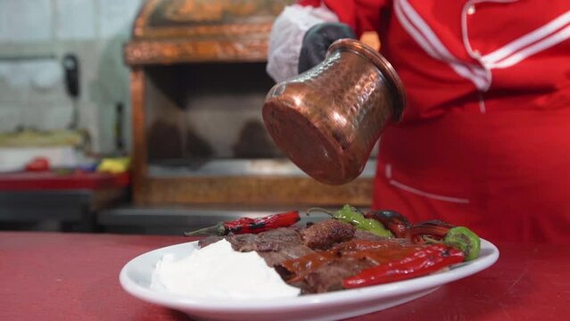 Turkey Iskender kebab. 
Pouring sauce on meat.
