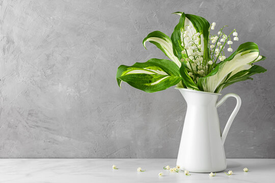 Lily of the valley flowers bouquet in vase on gray concrete background. womans day or wedding background