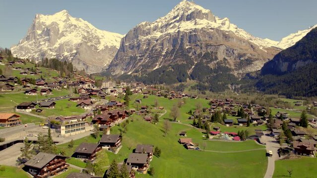 Aerial drone footage pushing out over picturesque mountain village grindelwald. Train and bus in front of swiss alps