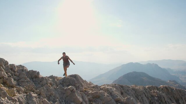 a girl walks along the ridge of a mountain against the background of the sky and mountains. mountain run. travel and adventure.