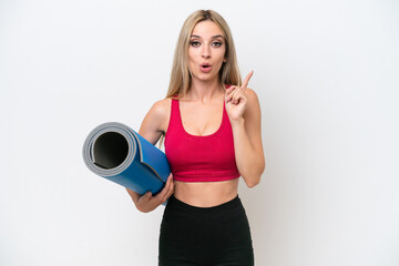 Young sport blonde woman going to yoga classes while holding a mat isolated on white background intending to realizes the solution while lifting a finger up