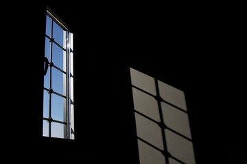 The light from the windows shines on the wall in the dark room.