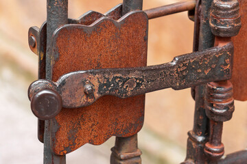 Ancient metal rusty wrought handle deadbolt (latch) of closed door of the lattice gate
