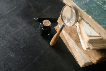 Stack of books, magnifying glass and inkwell with the