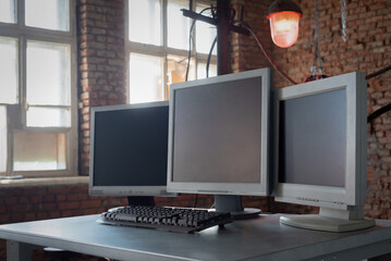 A blank screen computer monitors with copy space on the metal table background.
