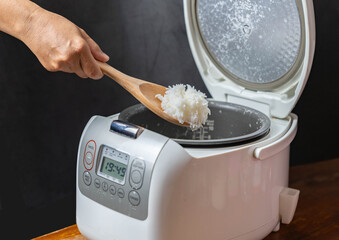 Rice cooking in electric rice cooker and scoop ladle.