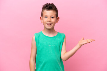 Little caucasian boy isolated on pink background holding copyspace imaginary on the palm to insert an ad