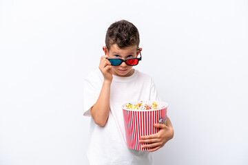 Little caucasian boy isolated on white background surprised with 3d glasses and holding a big bucket of popcorns