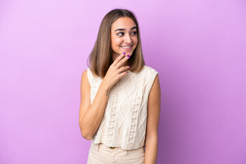 Young caucasian woman isolated on purple background looking up while smiling