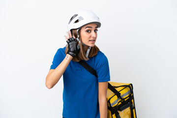 Young caucasian woman with thermal backpack isolated on white background listening to something by putting hand on the ear