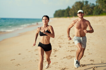 Healthy lifestyle. Jogging outdoors. Young man and woman is running on the sand beach.