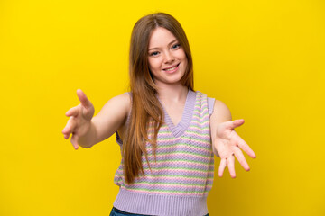 Young caucasian woman isolated on yellow background presenting and inviting to come with hand