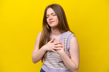 Young caucasian woman isolated on yellow background having a pain in the heart