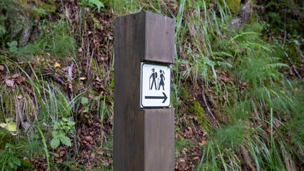 a wooden post with a sign and a roof to indicate a ban on entering the hiking trail or orientation arrows