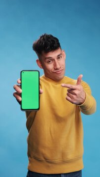 Man Showing A Smartphone With Green Screen While Standing Over An Isolated Background.